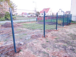 Metallzaun bei Wohngebiet und Straße.