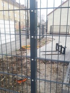 Metallzaun an Baustelle mit Gehweg im Hintergrund.
