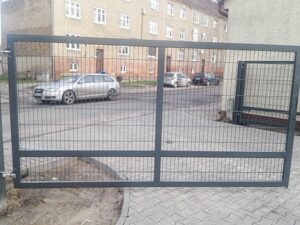 Metalltor vor Straße mit parkenden Autos.