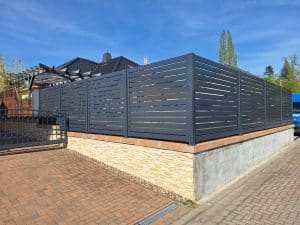 Moderner Metallzaun mit waagerechten Lamellen auf gemauerter Einfassung – gefertigt von Komabud Zaune .