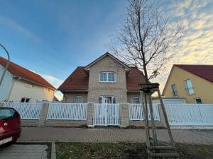Einfamilienhaus mit weißem Zaun bei Sonnenuntergang