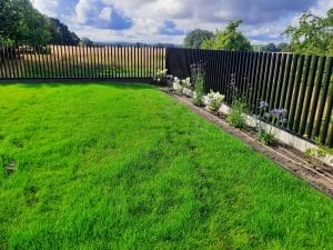 Gepflegter Garten mit Blumenbeet und Holzzaun.
