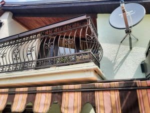 Balkon mit schmiedeeisernem Geländer und Satellitenschüssel