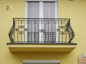 Schmiedeeiserner Balkon an gelbem Haus.
