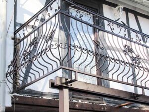 Verzierte Metallbalkonbrüstung an historischem Gebäude.