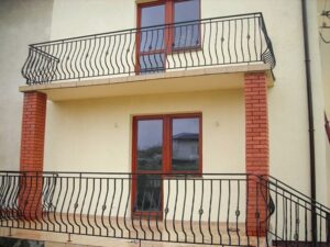 Balkon mit schmiedeeisernem Geländer und Ziegelstützen.