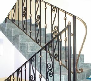 Schmiedeeisernes Geländer an Steintreppe im Innenraum.