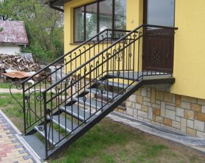 Metalltreppe außen an einem gelben Haus.