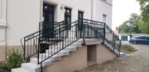 Treppe mit Geländer an Gebäudeeingang.