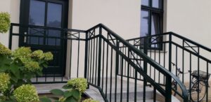 Grüne Metalltreppe mit Blumen und Fahrrad.