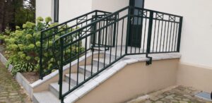 Außentreppe mit grünem Geländer und Pflanzen.