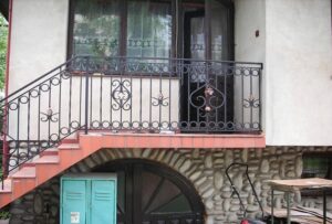Hausfassade mit schmiedeeisernem Balkon und Treppe.