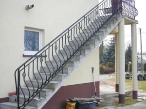 Außentreppe mit schmiedeeisernem Geländer an Gebäude.