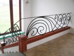 Schmiedeeisernes Geländer mit geschwungenen Linien und Holzpodest