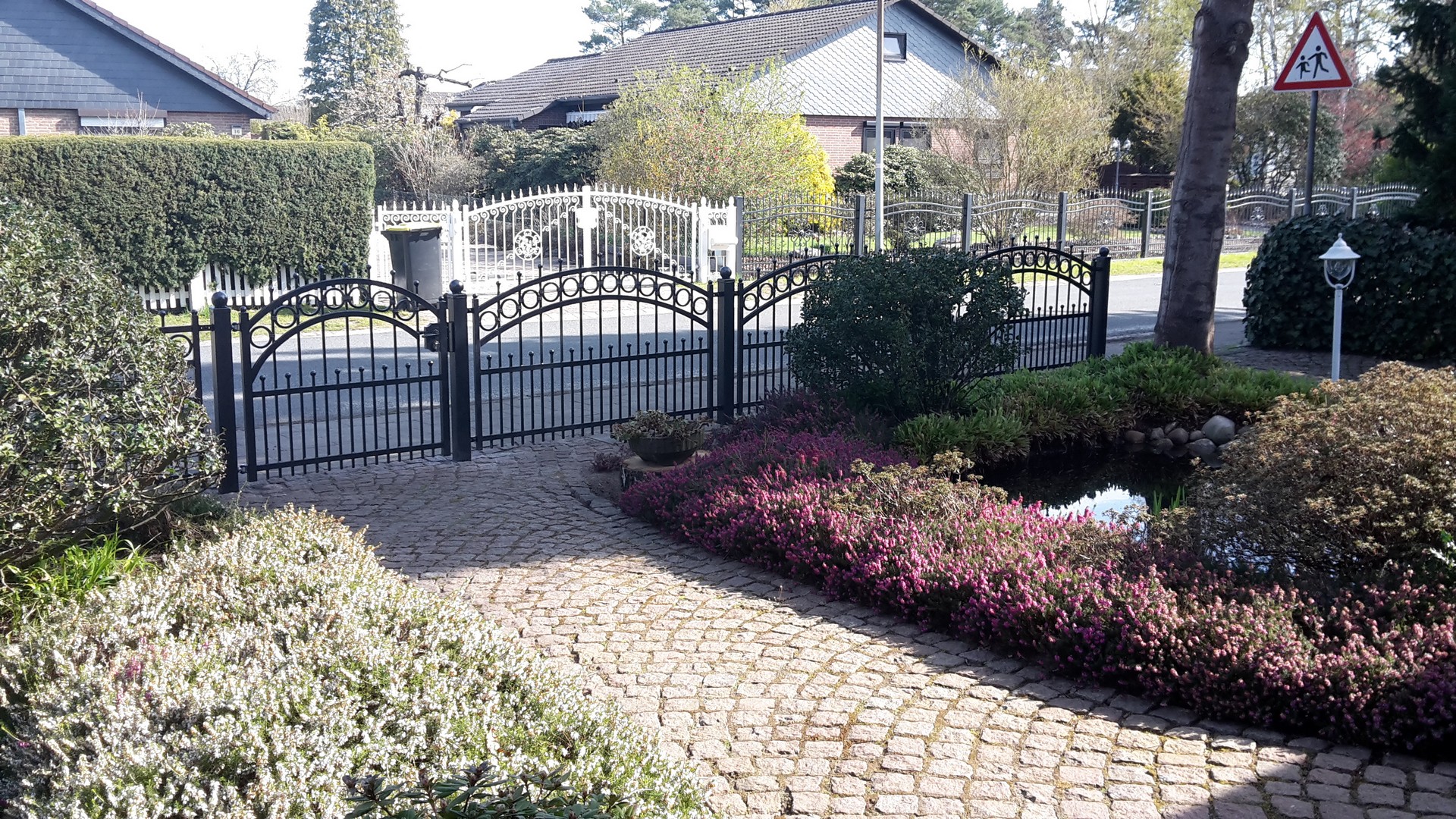 Elegantes Gartentor mit Kopfsteinpflasterweg und Hecken.