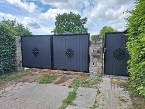 Dunkles Gartentor mit dekorativem Ornament und blickdichtem Paneeldesign – montiert zwischen Natursteinpfeilern.