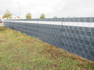 Dunkelgrauer Lärmschutzzaun an einer Straße.