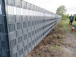 Lärmschutzzaun an einer Baustelle, Personen im Hintergrund.