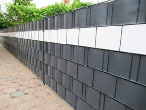 Schwarze Lärmschutzwand an einem Gehweg.