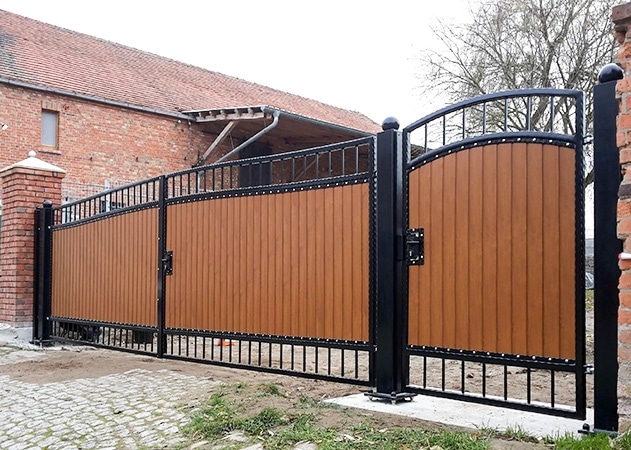 Schmiedeeisernes Tor an einem Backsteinhaus.