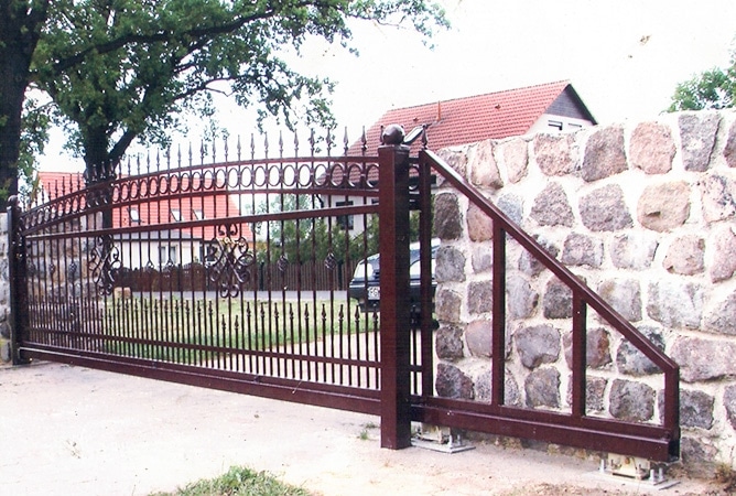 Schmiedeeisernes Tor an einer Steinmauer.