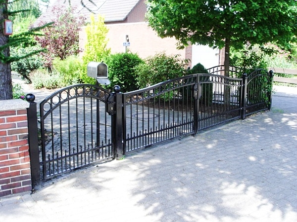 Schmiedeeiserne Gartentor und Zaun, Wohnhaus im Hintergrund.