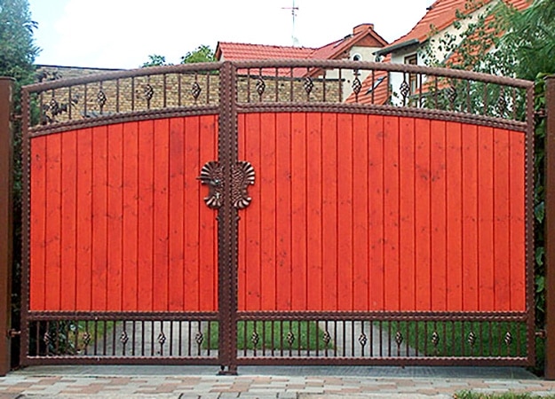 Rotes Gartentor mit Löwenkopf-Dekor.