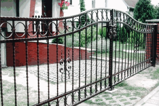 Schmiedeeisernes Tor vor einem Einfamilienhaus.