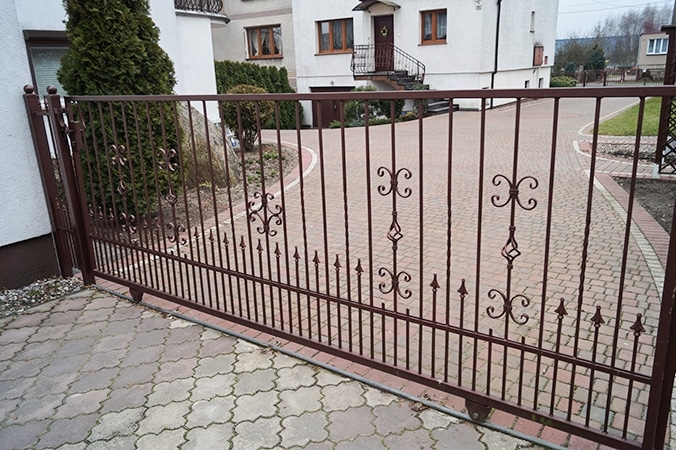 Verziertes Metalltor vor Einfamilienhaus.