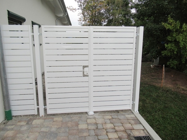 Weiße Gartentür aus Metall mit Lamellen.