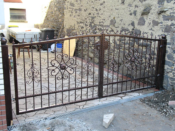 Eisernes Tor mit dekorativen Elementen, Baustelle im Hintergrund.
