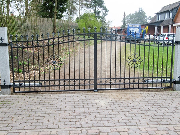 Schmiedeeisernes Tor mit Verzierungen und Einfahrt.