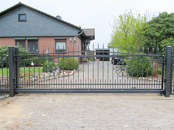 Metalltor vor einem Einfamilienhaus mit Einfahrt.