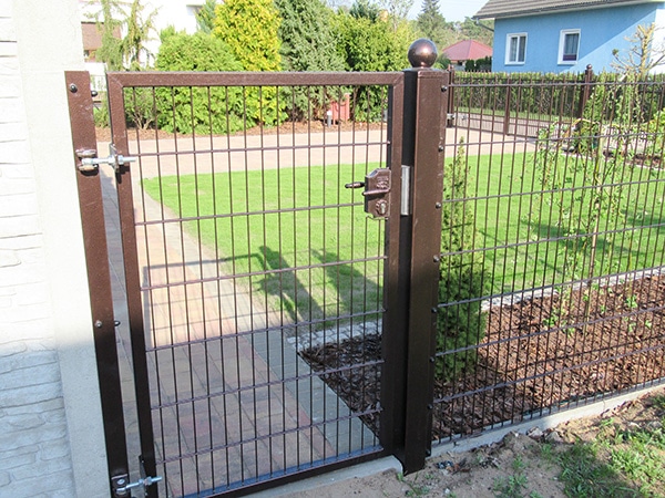 Braunes Gartentor mit Metallzaun und Rasen.