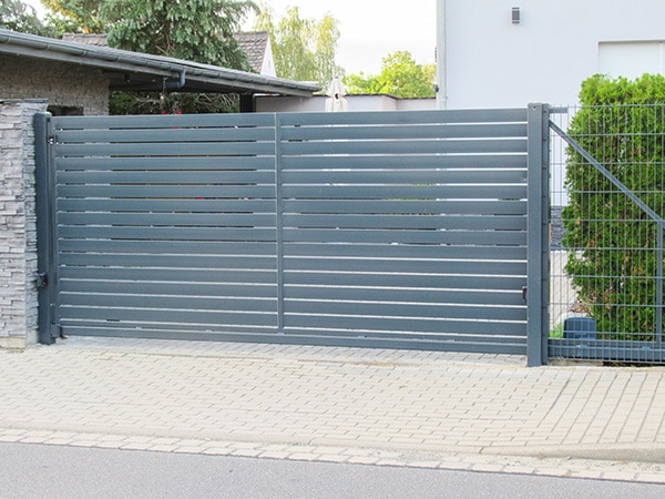 Graues Metall-Schiebetor an Einfahrt.