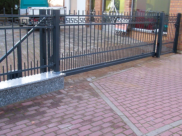 Schmiedeeisernes Tor vor Einfahrt mit Pflastersteinen.