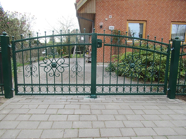 Grünes schmiedeeisernes Tor vor einem Haus.