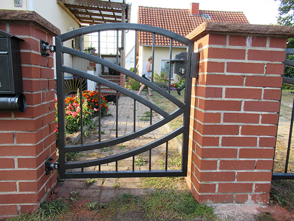 Ziegelsteinsäulen mit schwarzem Metallgartenzaun.