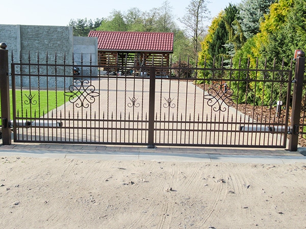 Schmiedeeisernes Gartentor mit Einfahrt und Grünanlage