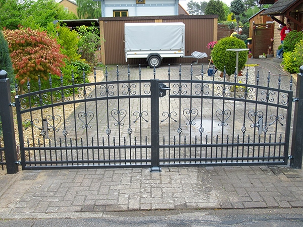 Schmiedeeisernes Tor vor Einfahrt mit Anhänger.