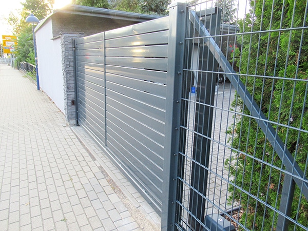Metalltor und Zaun an Gehweg.