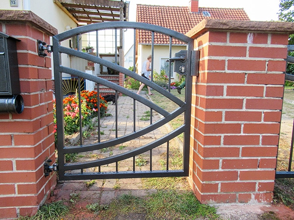 Metallgartenzaun, Ziegelsteinsäulen, ländliches Haus.
