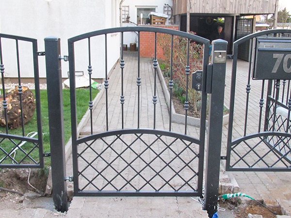 Schmiedeeisernes Gartentor vor einem Haus.