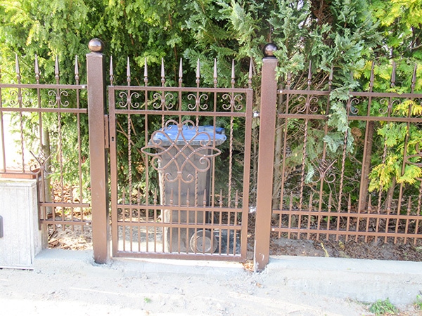 Verzierter Eisentor-Eingang mit Hecke.