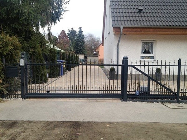 Einfahrt mit schmiedeeisernem Tor und Einfamilienhaus
