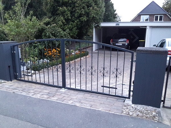 Metallgartentor an einer Einfahrt mit Auto im Hintergrund.