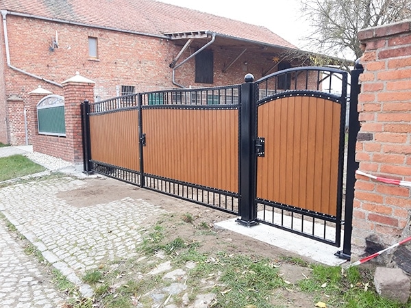 Neues, braunes Metalltor vor Ziegelhaus.