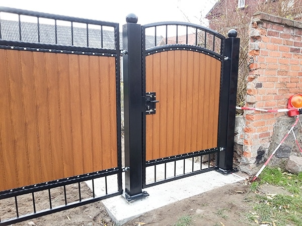 Hölzernes Gartentor mit Metallrahmen und Mauer.