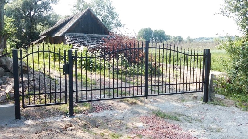 Schmiedeeisernes Tor vor ländlichem Grundstück.