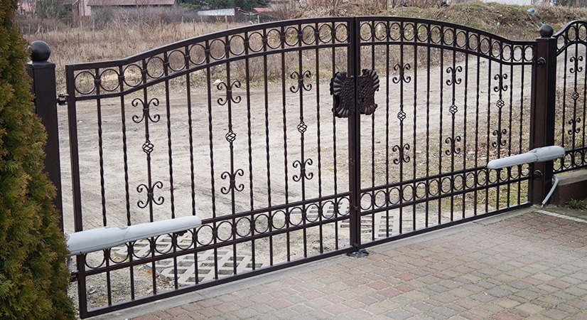 Schmiedeeisernes Tor mit Zierelementen und Auffahrt.